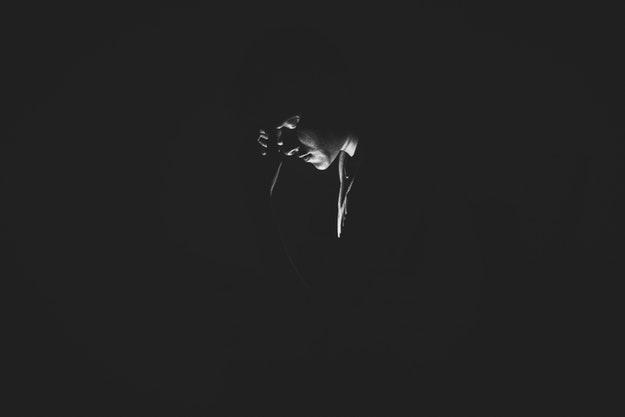 Man in the dark with hand on his forehead.