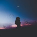 Silhouette of a woman looking to the night sky.