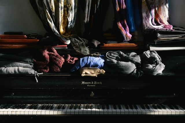 Clothes scattered on a piano.