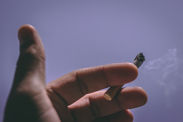 A hand holding a lit cigarette.