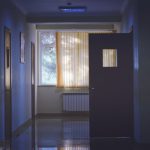 A dark hospital hallway with a door propped open.
