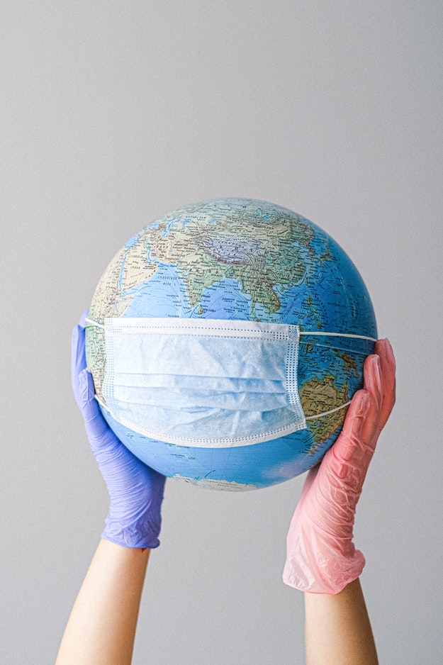 Hands with latex gloves holding a masked world