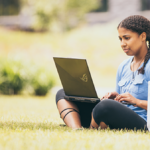 Woman writing on laptop while sitting outside