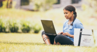 Woman writing on laptop while sitting outside