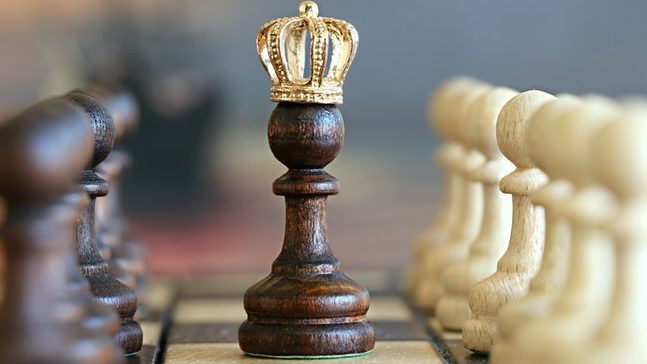 Kings crown placed onto a pawn in the center of a chess board