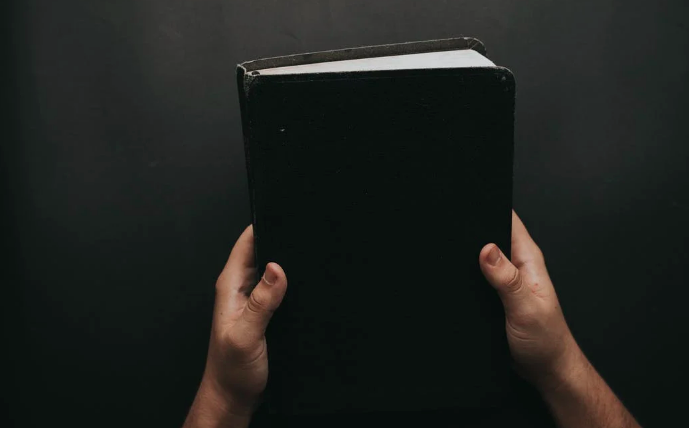 A pair of hands hold up a black book.
