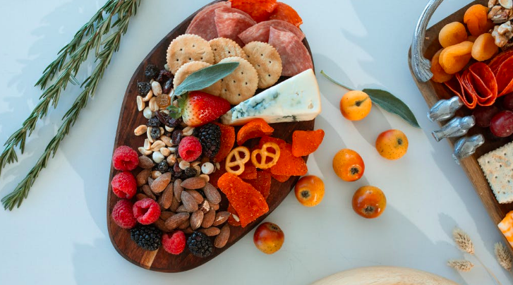 A charcuterie board with meats, cheeses and fruits on a white table.