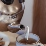 A kettle pouring water into a tea cup