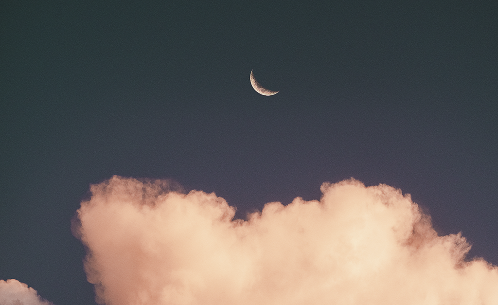 A crescent moon and cloud in the night sky.