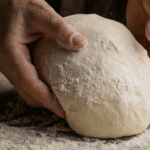 A pair of hands kneading dough in flour