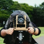 A photographer with head covered taking a photo with an antique camera