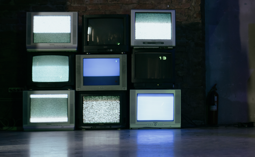 A stack of vintage televisions displaying static channels