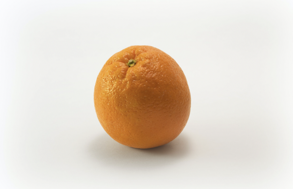 An orange in front of a white background