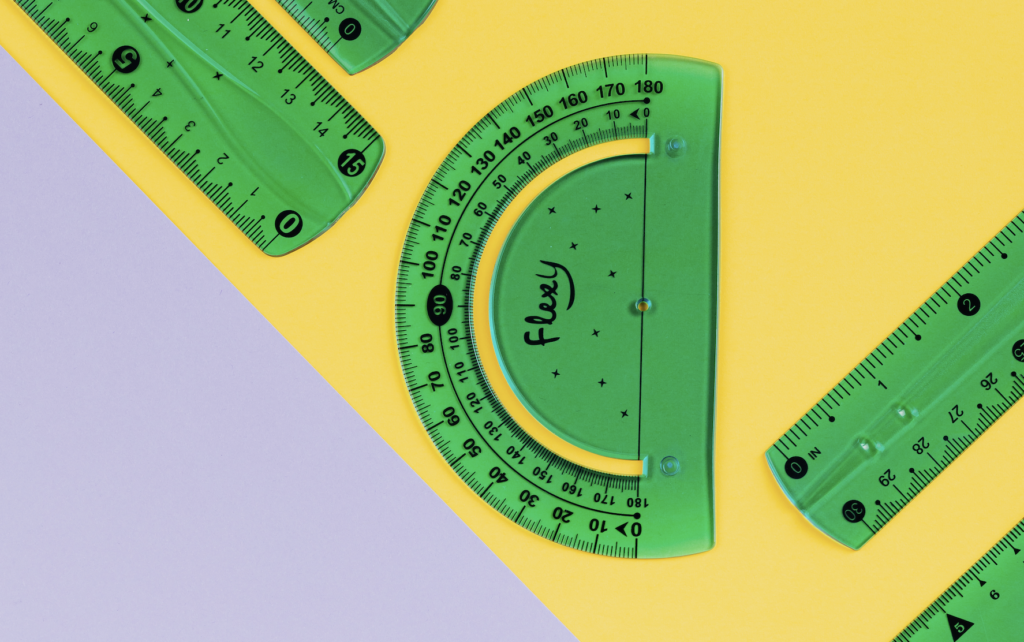 Green protractors and rulers on a yellow and gray background.