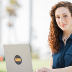 curly-haired woman sitting at a laptop