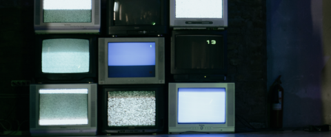 A stack of vintage televisions displaying static channels