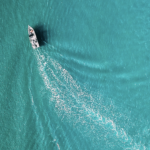 Above view of a boat leaving ripples in open water