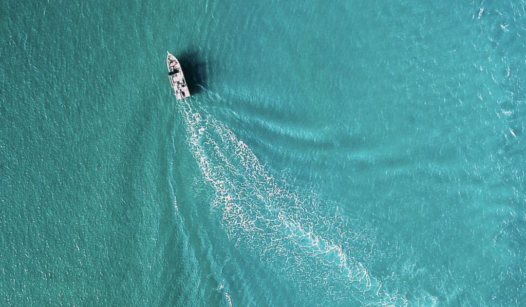 Above view of a boat leaving ripples in open water