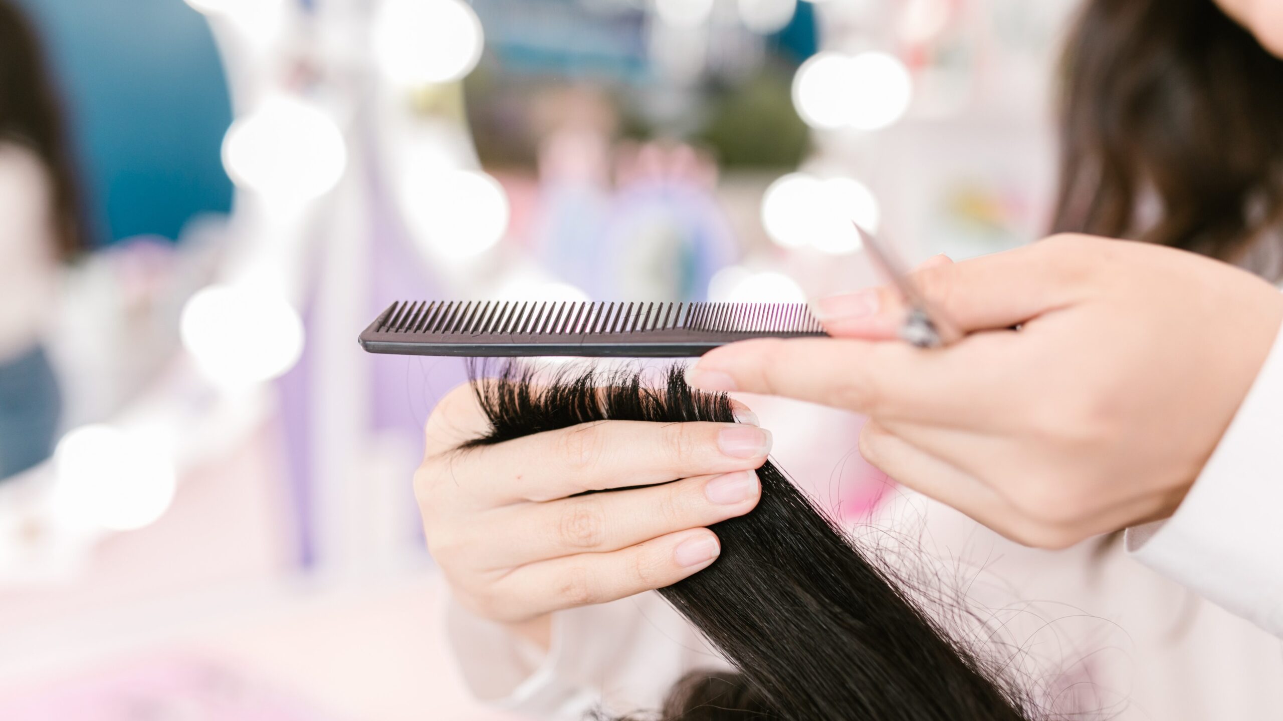 Hairdresser holding hair, comb and scissors