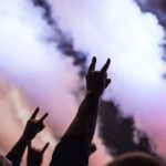 Fans holding up rock hand signs at a concert