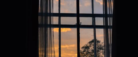 View of a sunrise through a curtained window